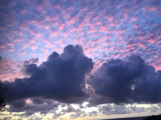 Kauai sunset with small clouds sprayed across sky in pinks and purples.